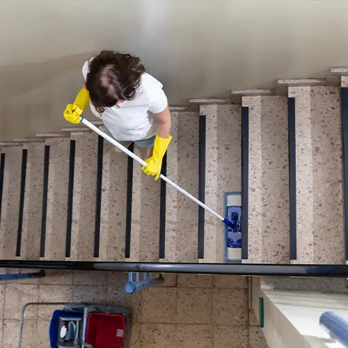 Frau während Treppenhausreinigungsarbeiten